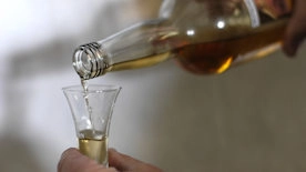 Ausschenken von Schnaps in ein Glas Ausschenken von Schnaps in ein Glas